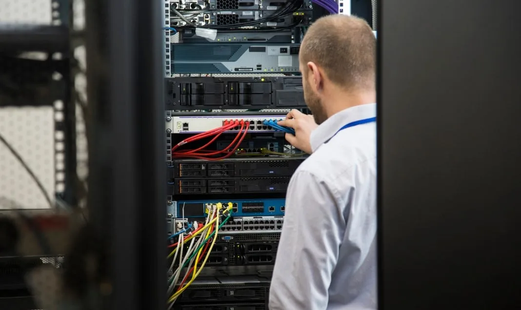 Tecnico TN Solutions collega i cavi di rete in un armadio rack