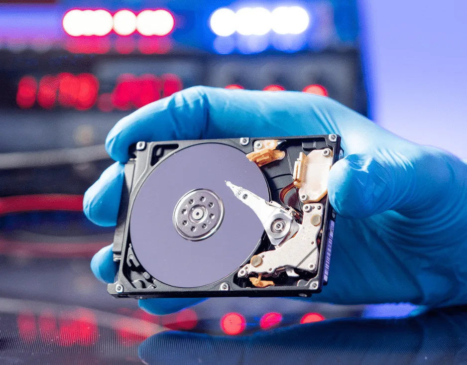 Tecnico al lavoro sul recupero dati di un disco danneggiato in laboratorio