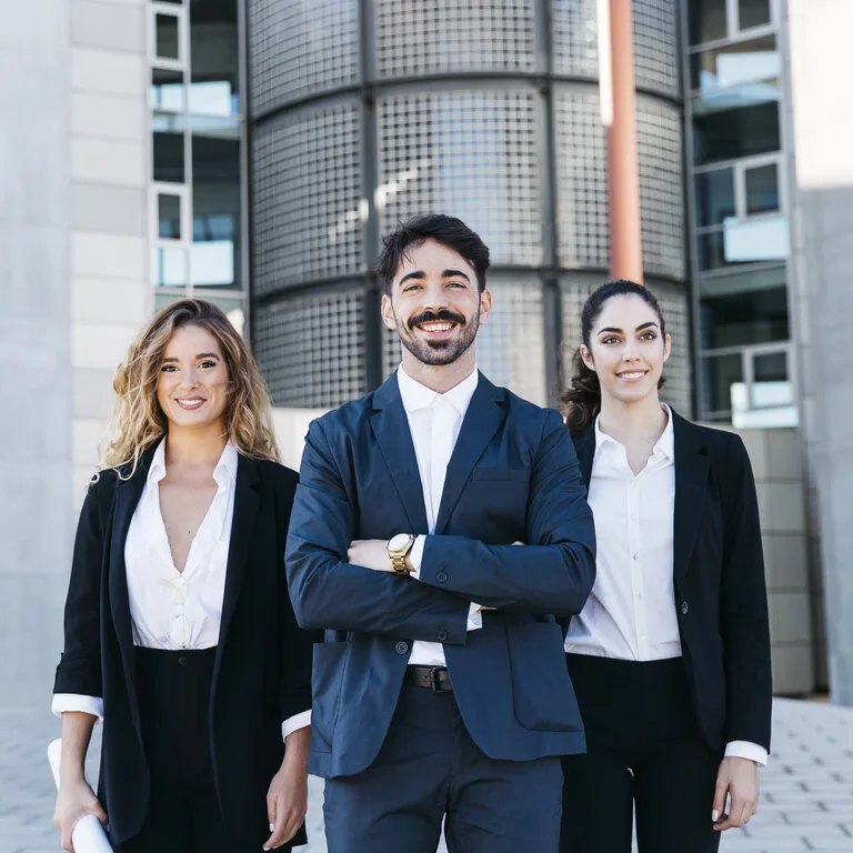 Team of professionals in business attire from an SME standing in front of a modern building